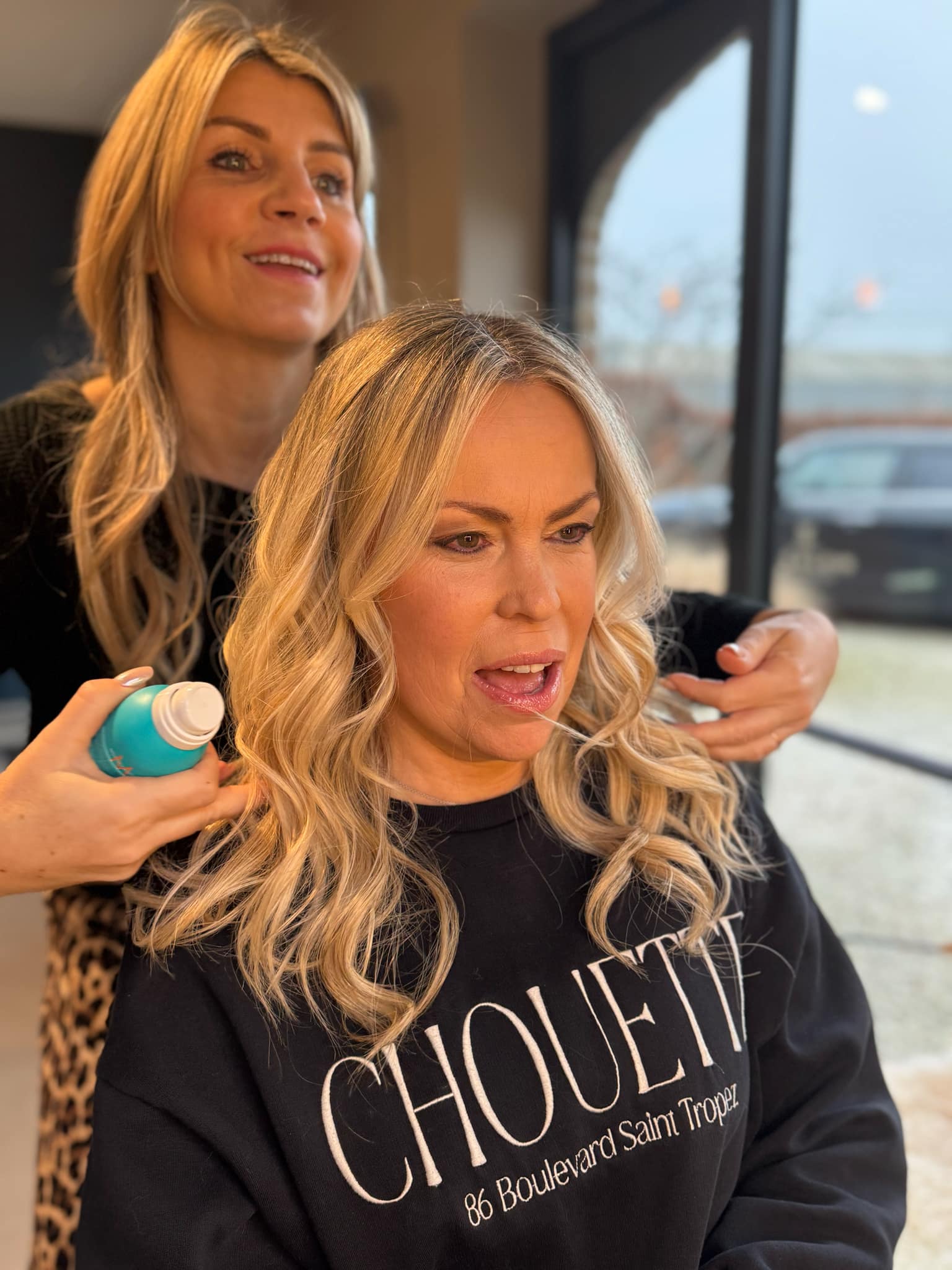 Kapster stylet het haar van de klant met een product van Moroccanoil